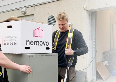 To flyttemænd fra Nemovo med løfteseler gør et pengeskab klar til flytning