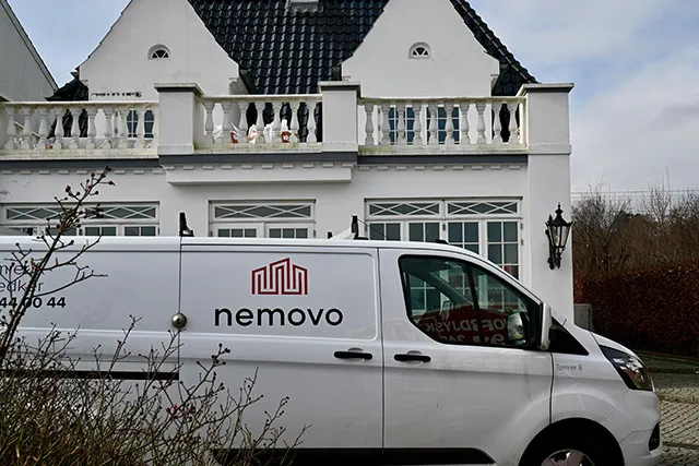 Hvid varevogn fra Nemovo parkeret foran en stor hvid villa