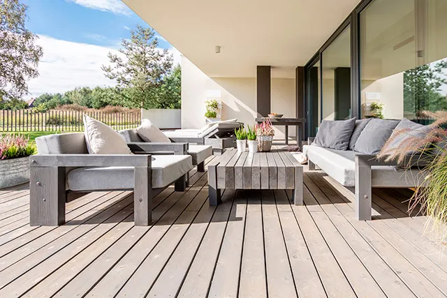Overdækket terrasse med gråbehandlet trædæk og havemøbler i træ